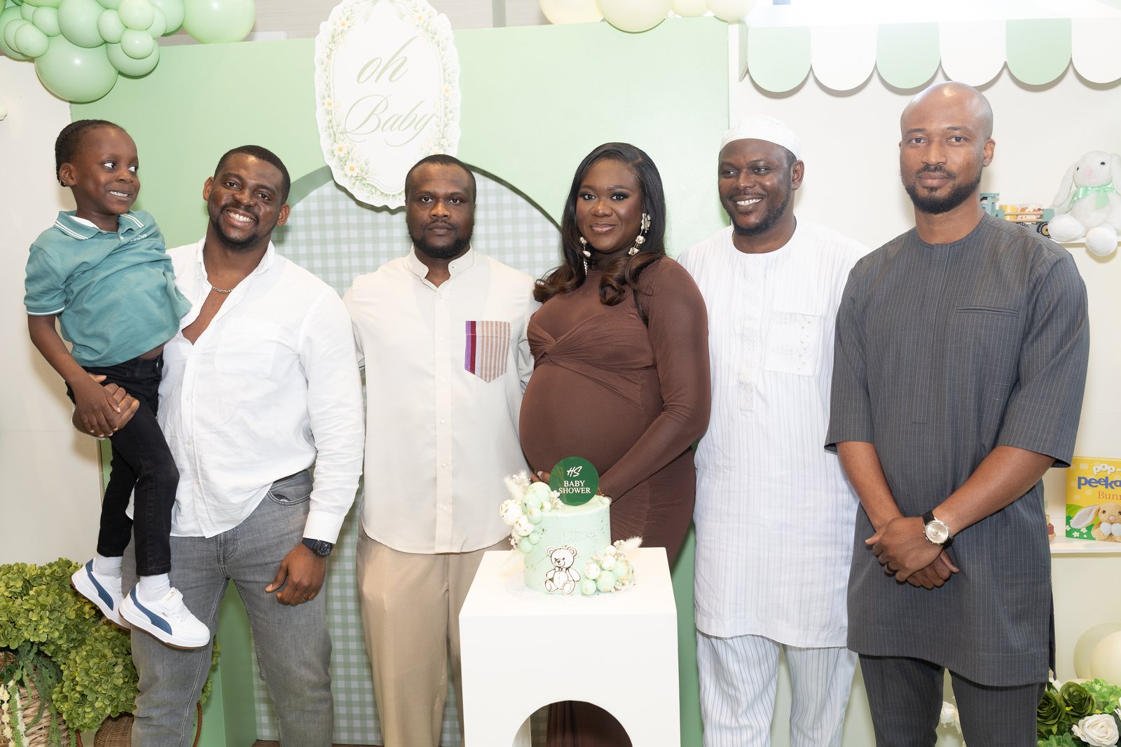 Extended family group portrait with the parents-to-be beside the cake and balloon garland