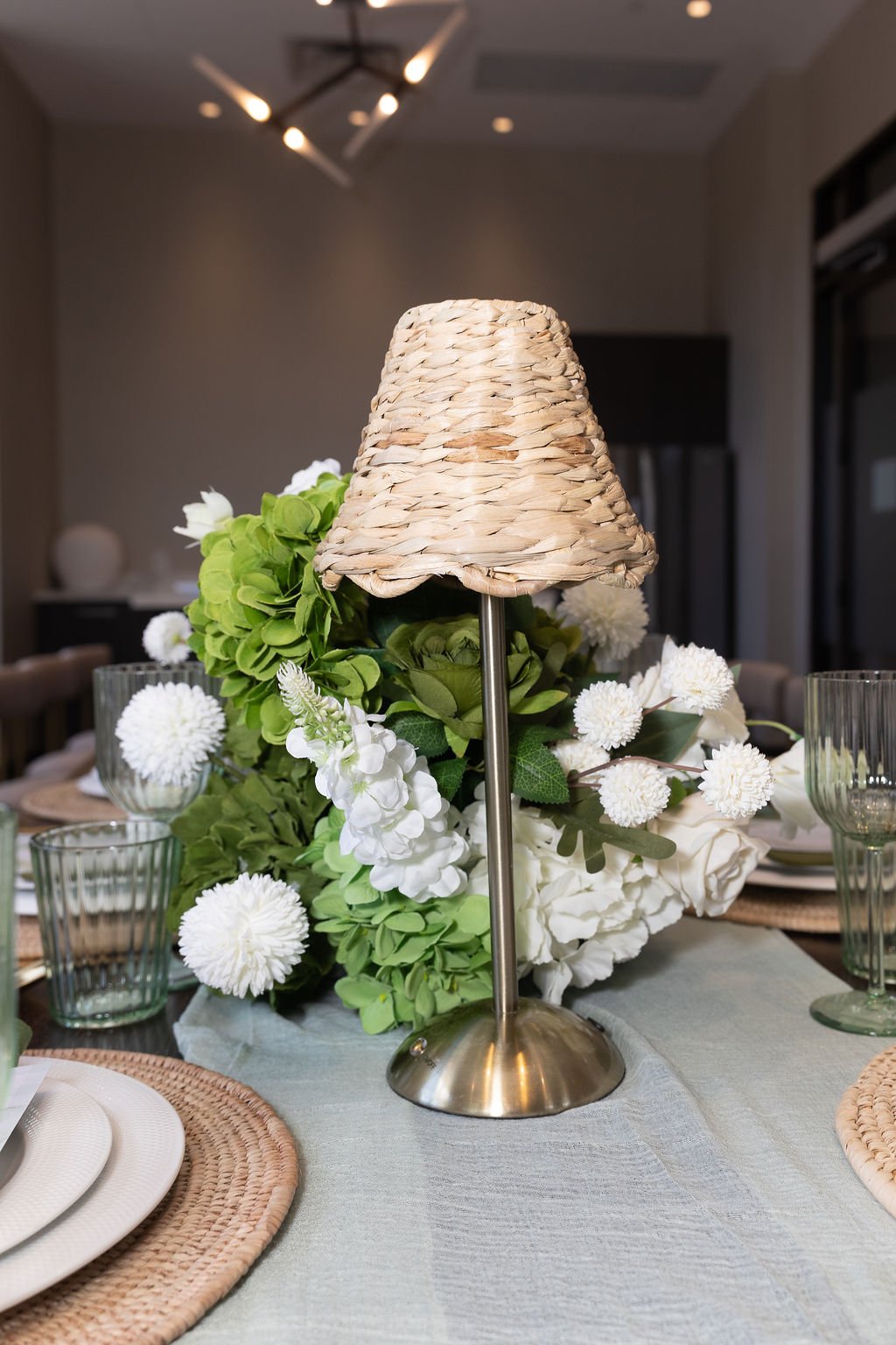 Reception table centerpiece with woven lampshade and white and green florals