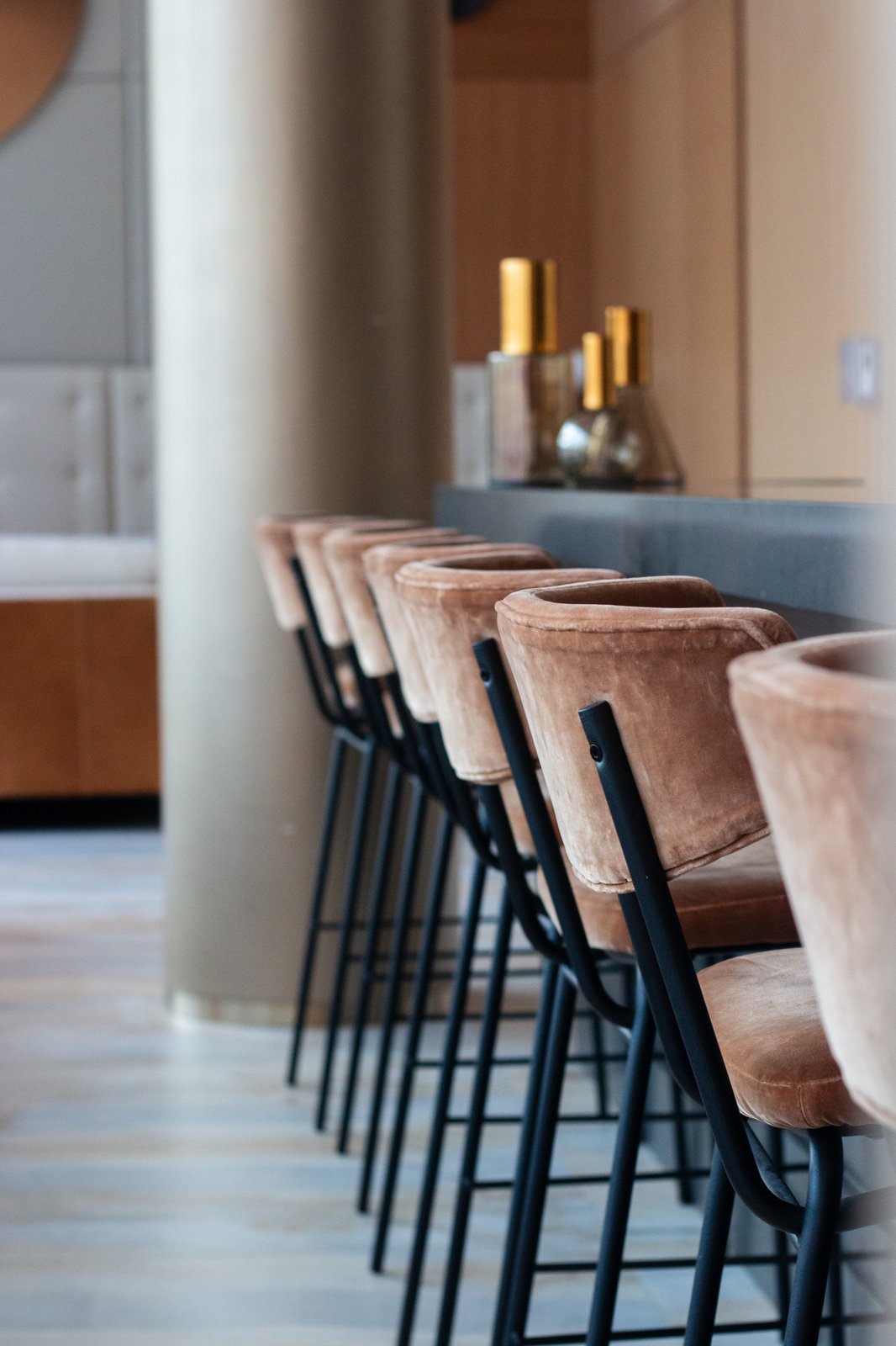 Row of blush velvet bar stools along a sleek lounge counter