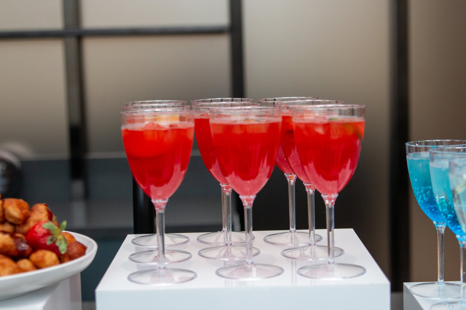 Rows of red and blue signature mocktails served in stemmed glasses