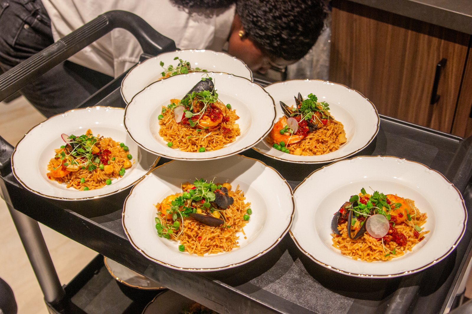 Plated seafood jollof rice with shrimp and mussels, garnished with microgreens