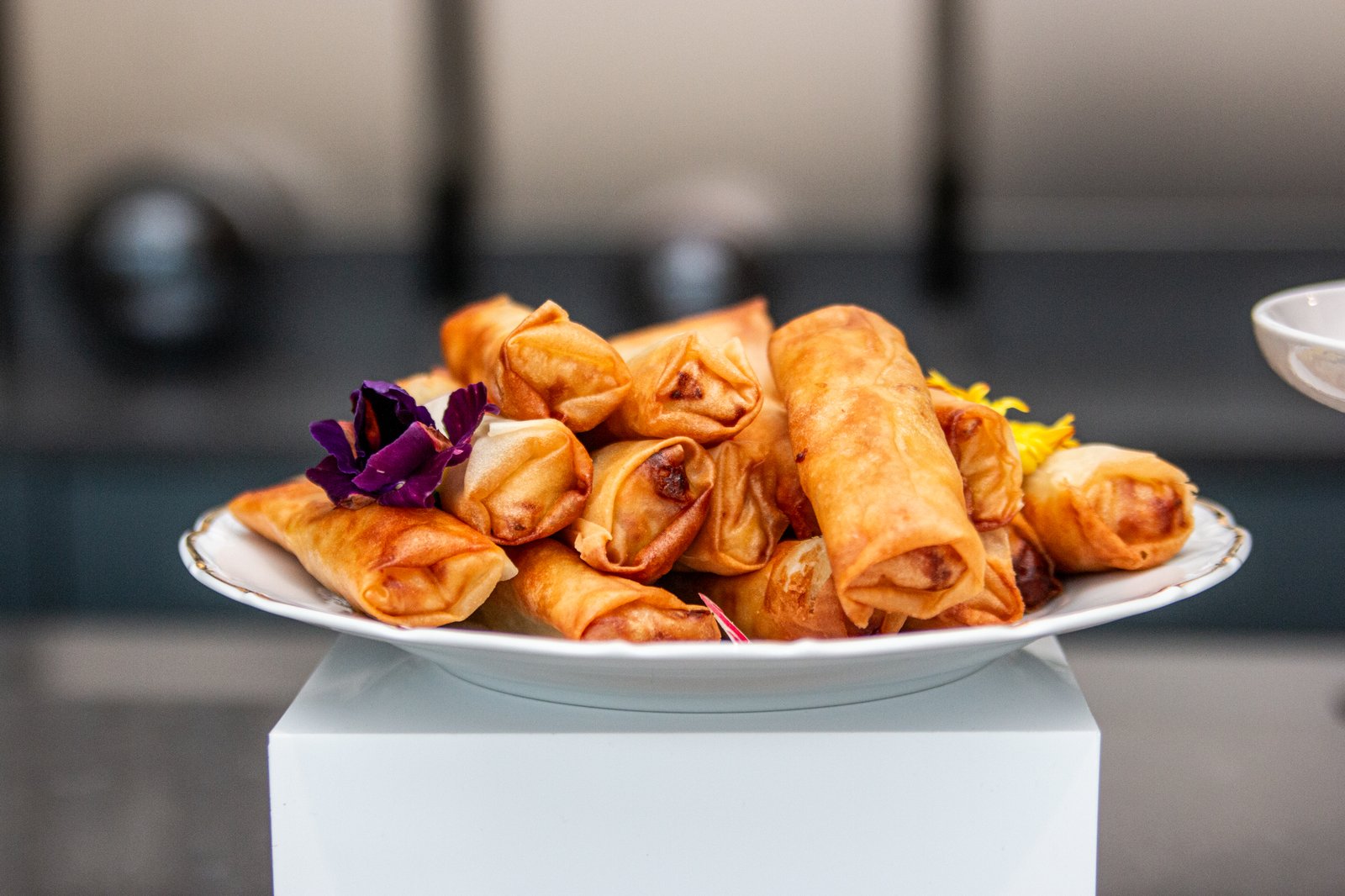 Platter of golden fried spring rolls garnished with edible flowers