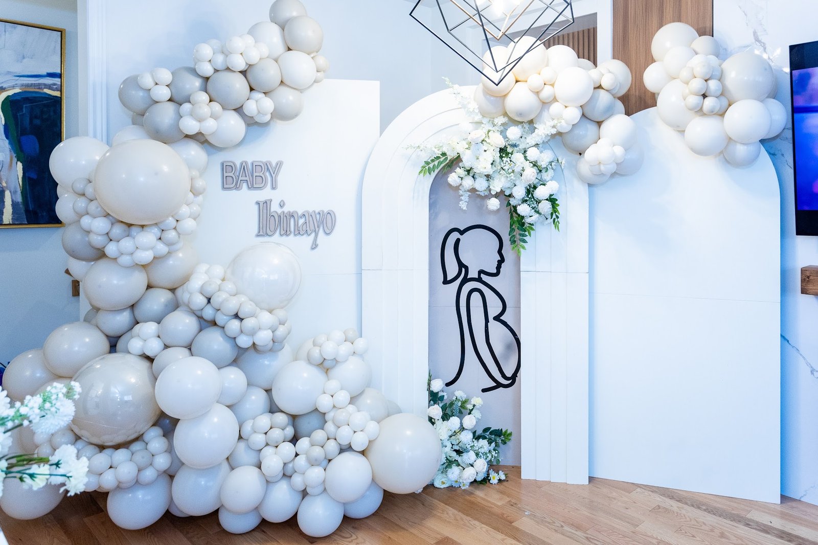 Arched balloon backdrop with a floral crown and pregnant silhouette line art