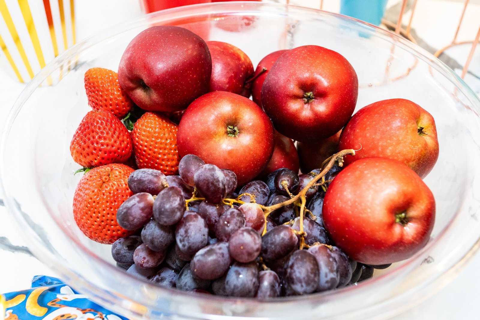 Fresh fruit bowl with apples, strawberries, and grapes on the refreshments table