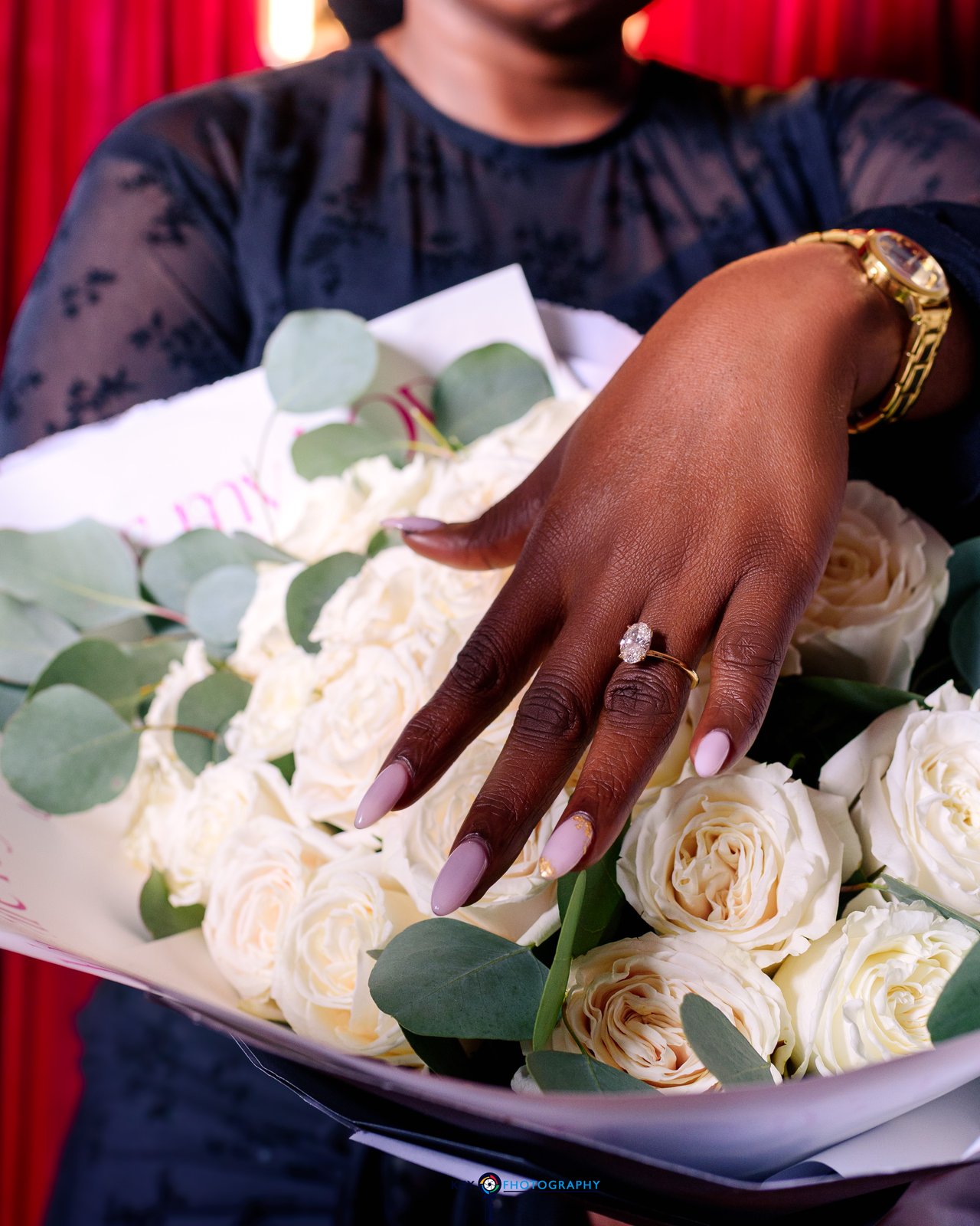 Close-up of the engagement ring on her hand resting among white roses