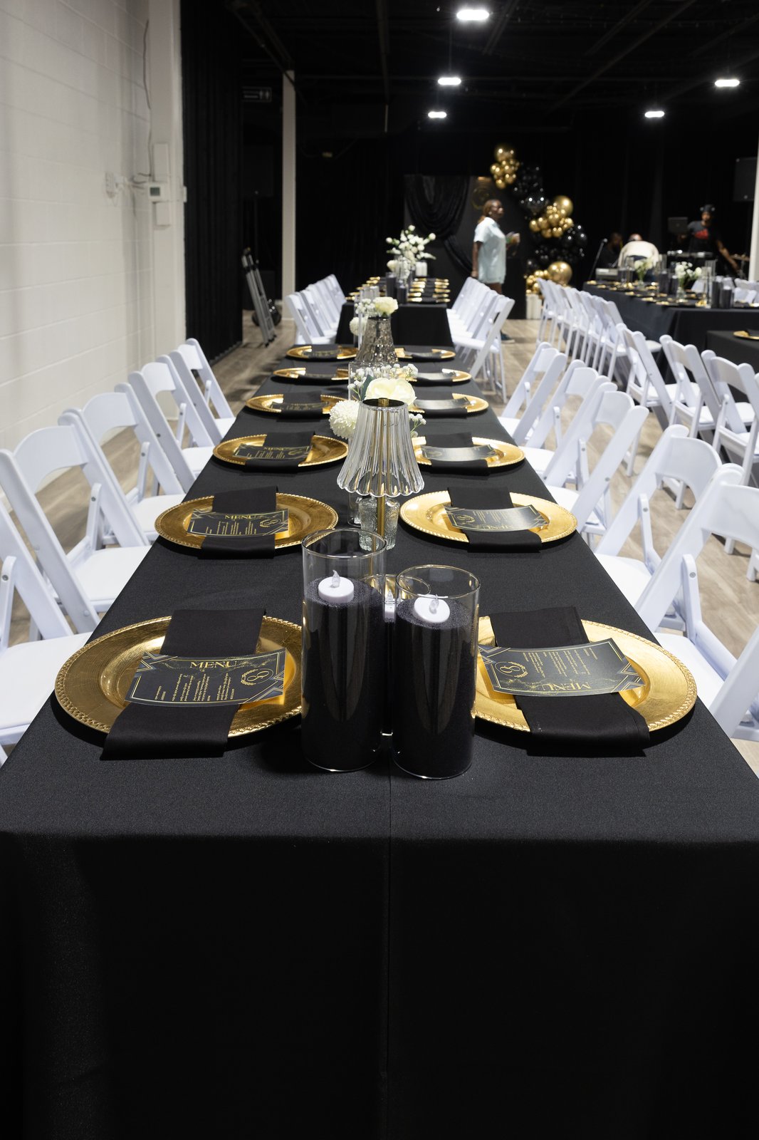 Elegant table setting with gold chargers, menu cards, and candle centerpieces