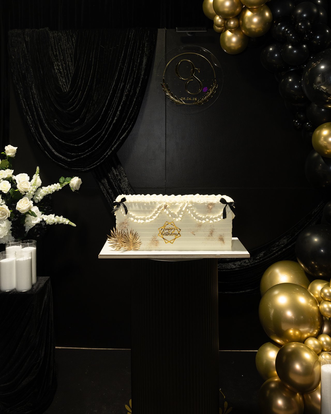 Full backdrop view with birthday cake, florals, and balloon garland