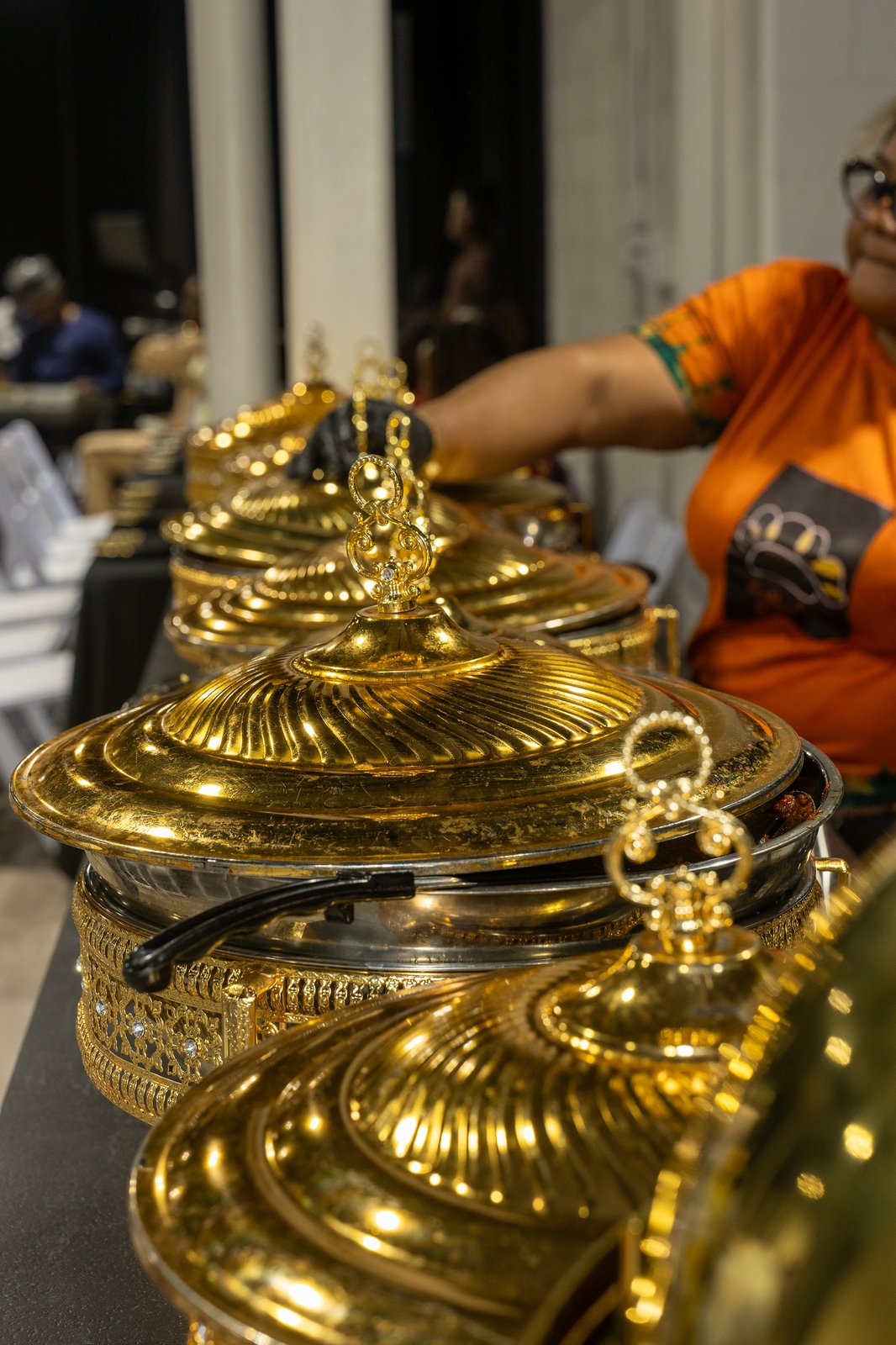 Row of ornate gold chafing dishes on the catering display