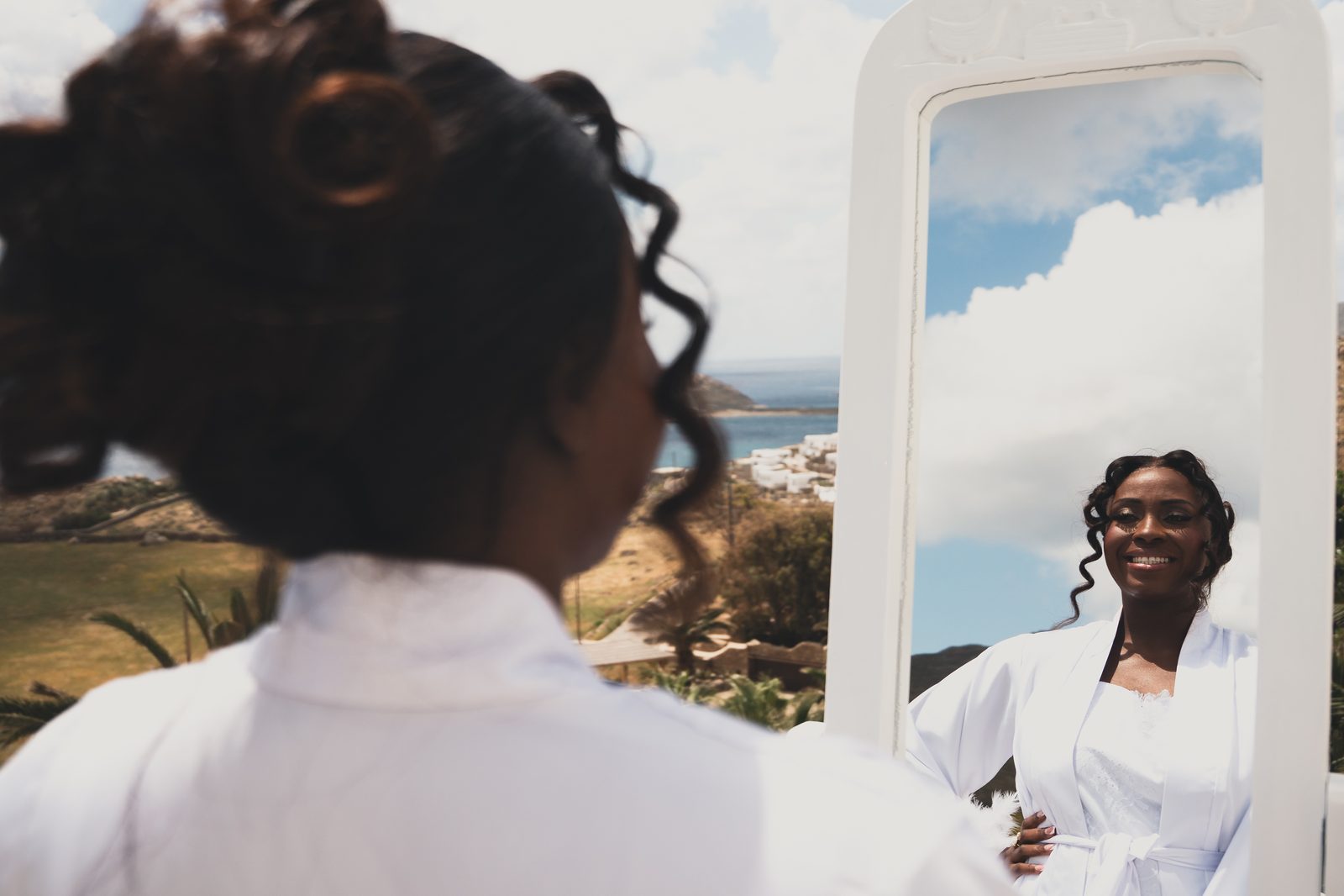 Bride having her hair styled with an ocean view in the background