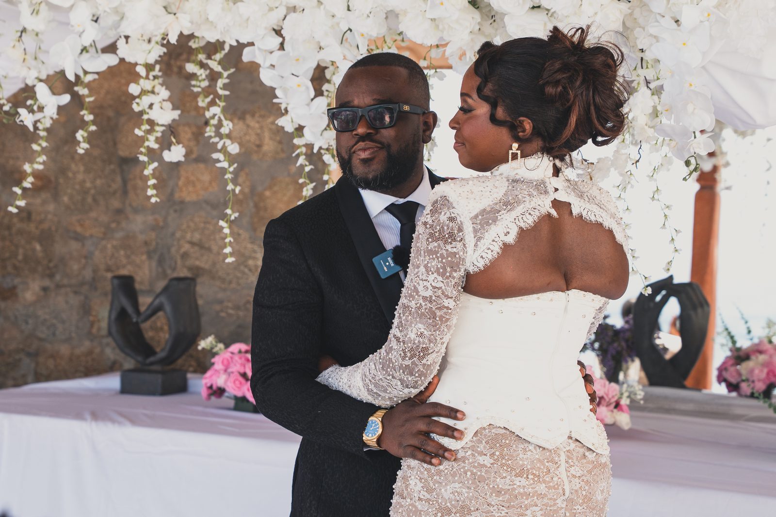 The couple embracing under the ceremony arch