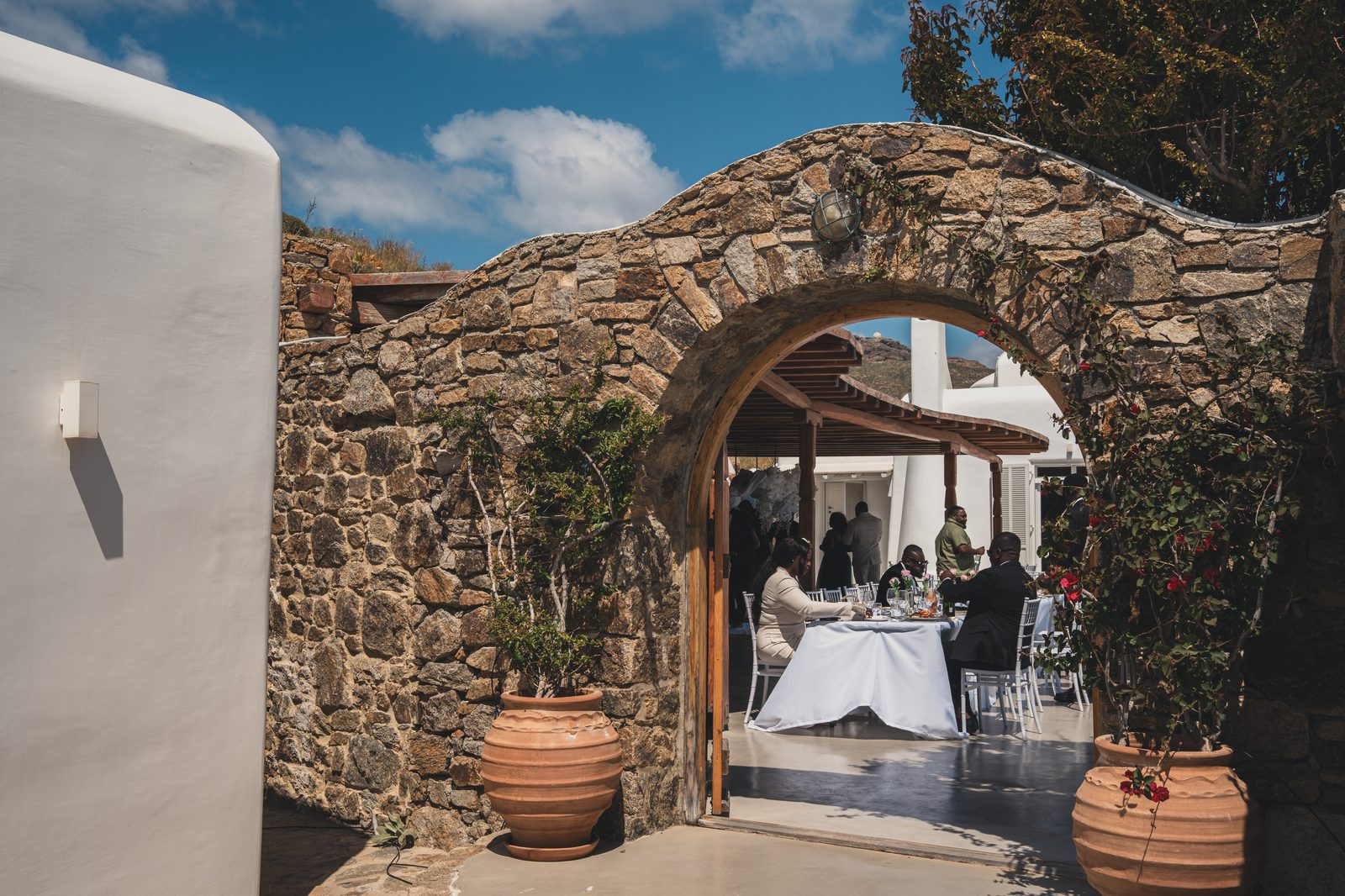 Reception dining table framed by a stone archway with terracotta urns and greenery