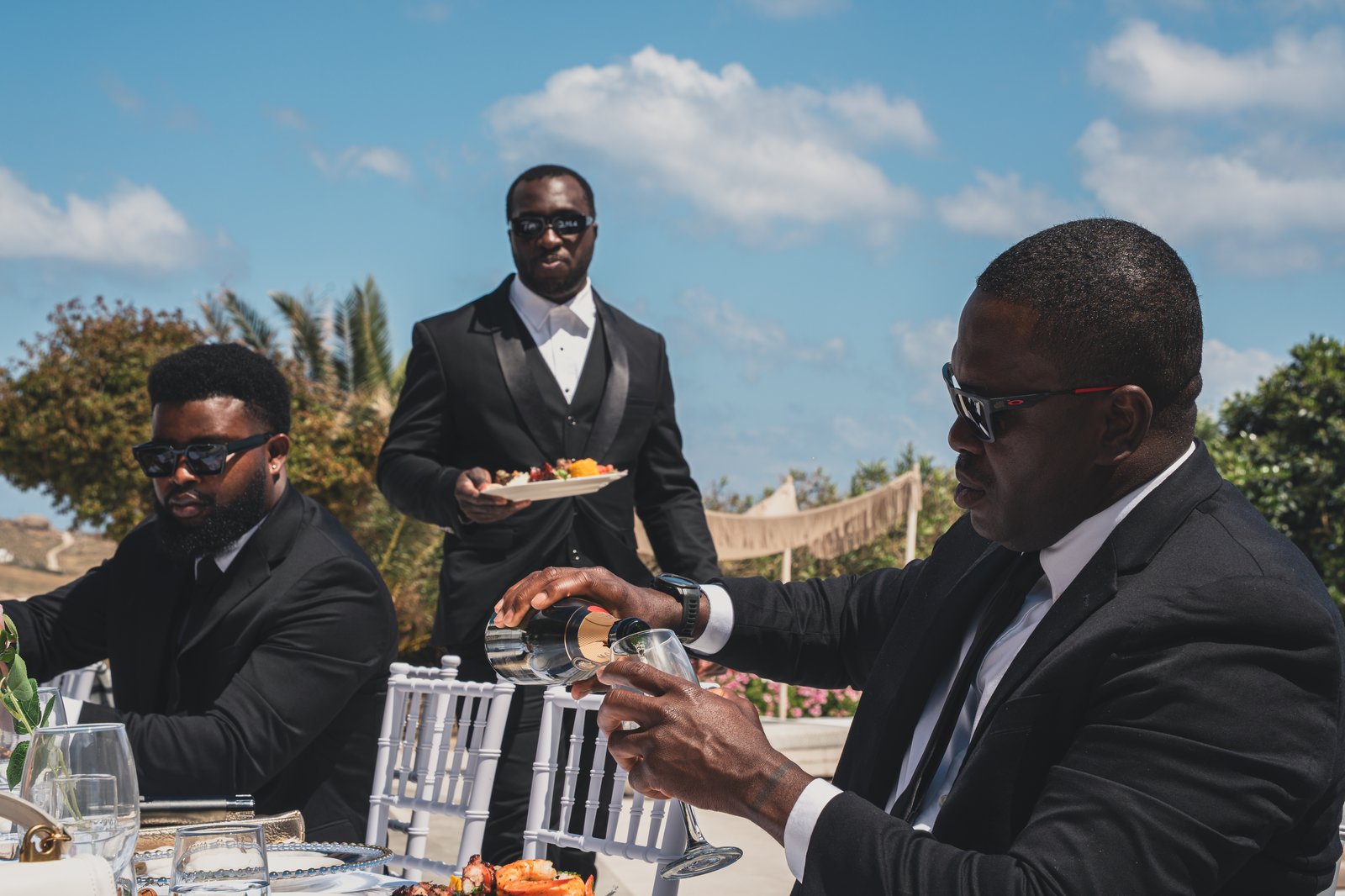 A groomsman carrying a plate of grilled seafood and vegetables to the reception table