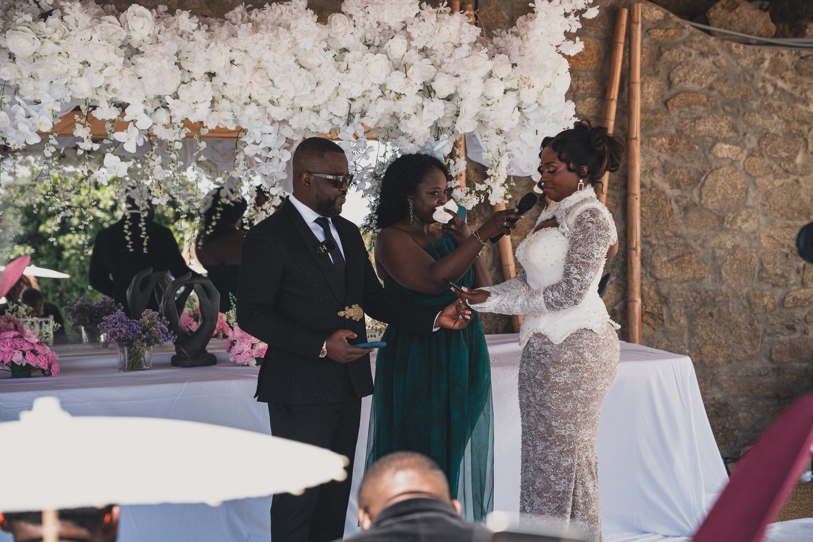 The couple embracing under a floral arch during the vow renewal ceremony
