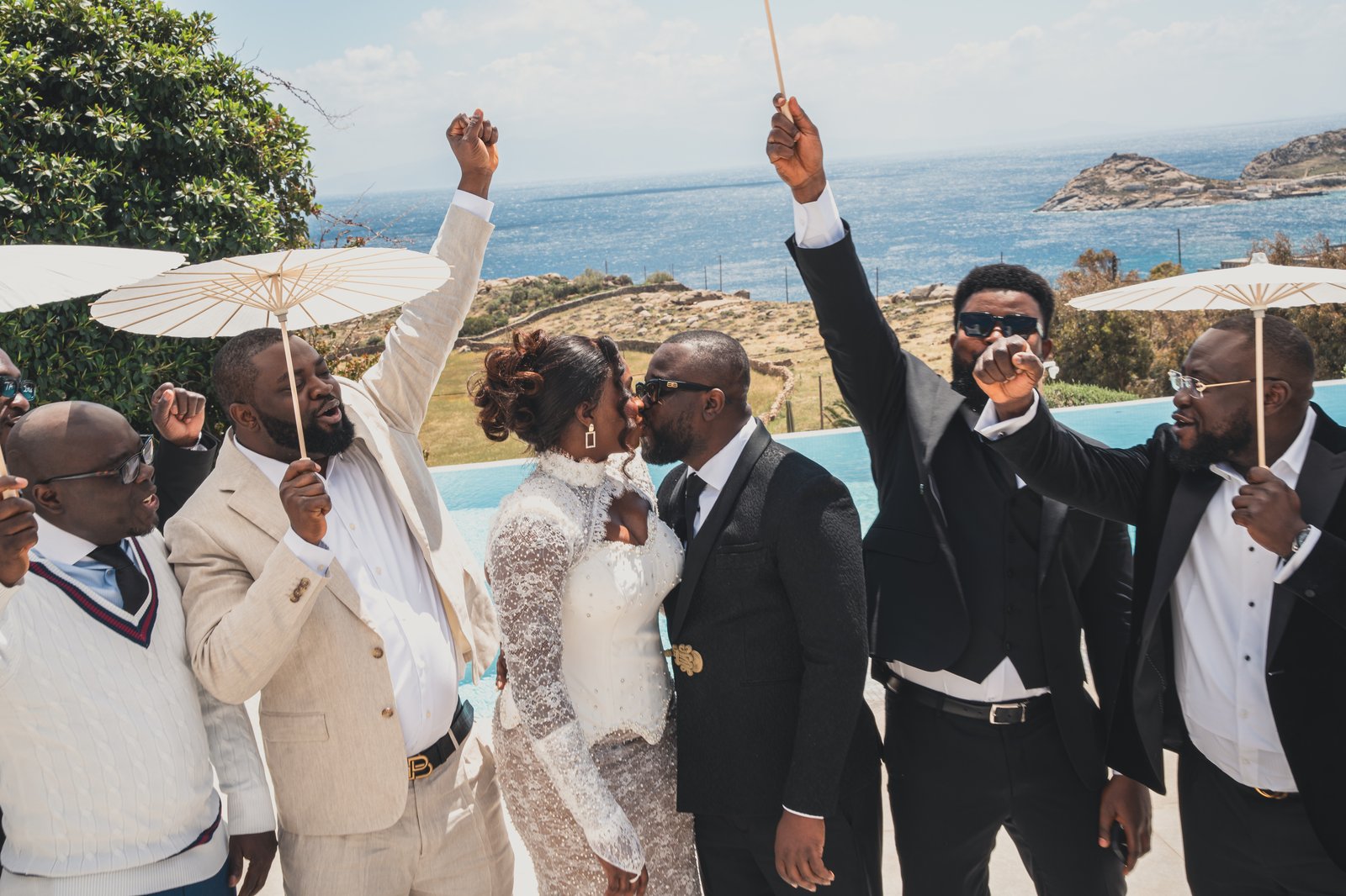 Groomsmen in white and black suits raising their canes in celebration