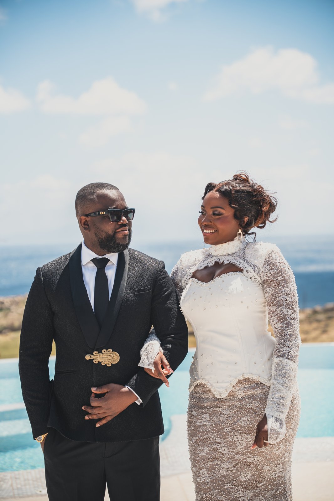 The couple posing together, the bride in a lace gown and the groom in a dark suit