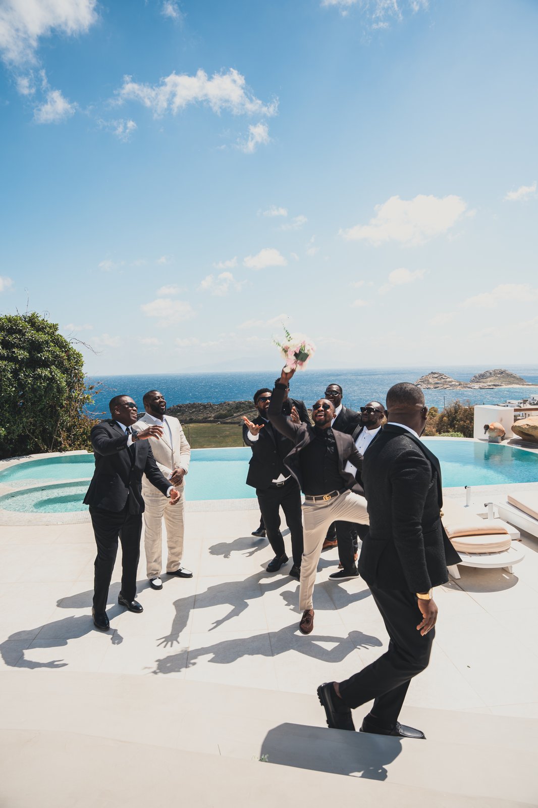 Groomsmen cheering poolside with their arms raised