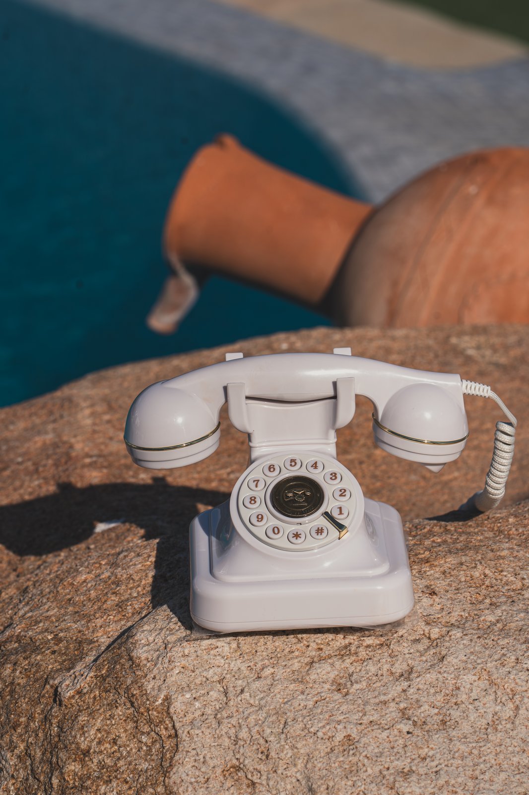 A vintage white telephone styled as a decor detail beside the pool