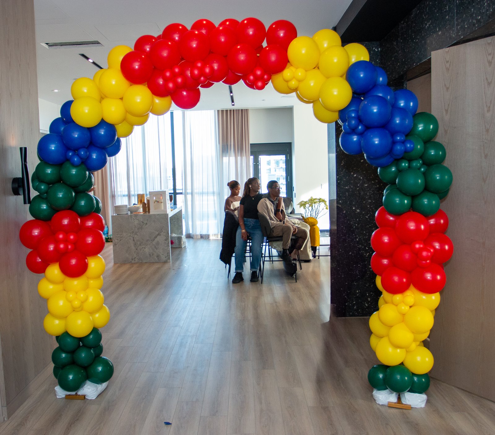A balloon arch in red, yellow, blue and green welcoming guests into the party