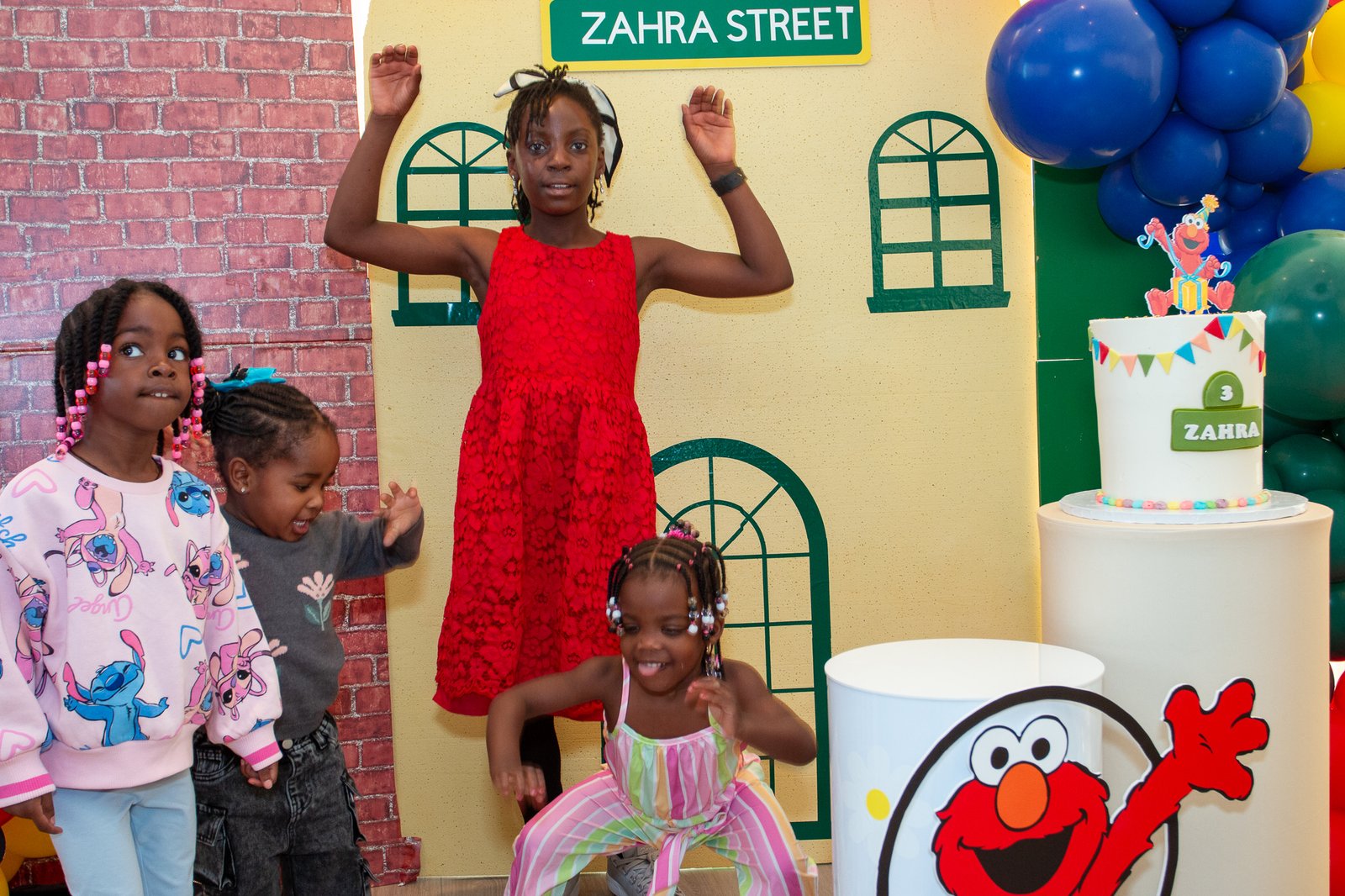 Two girls posing together at the "Zahra Street" Sesame Street-themed photo backdrop